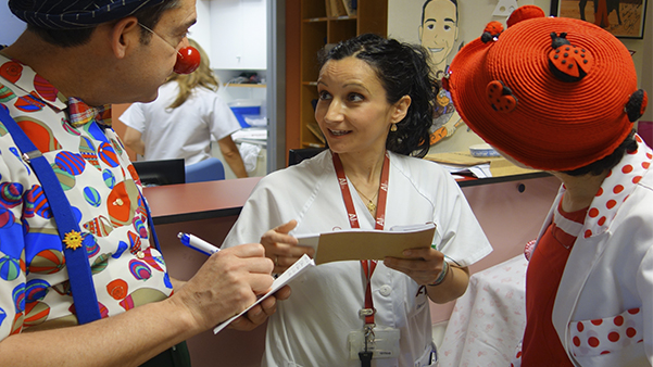 Fig. 4. Los pupaclown, antes de comenzar a visitar a los pacientes, en el momento de la trasmisión, cuando el personal sanitario les facilita los datos clínicos necesarios. (Fotógrafo: E. Martínez Bueso).